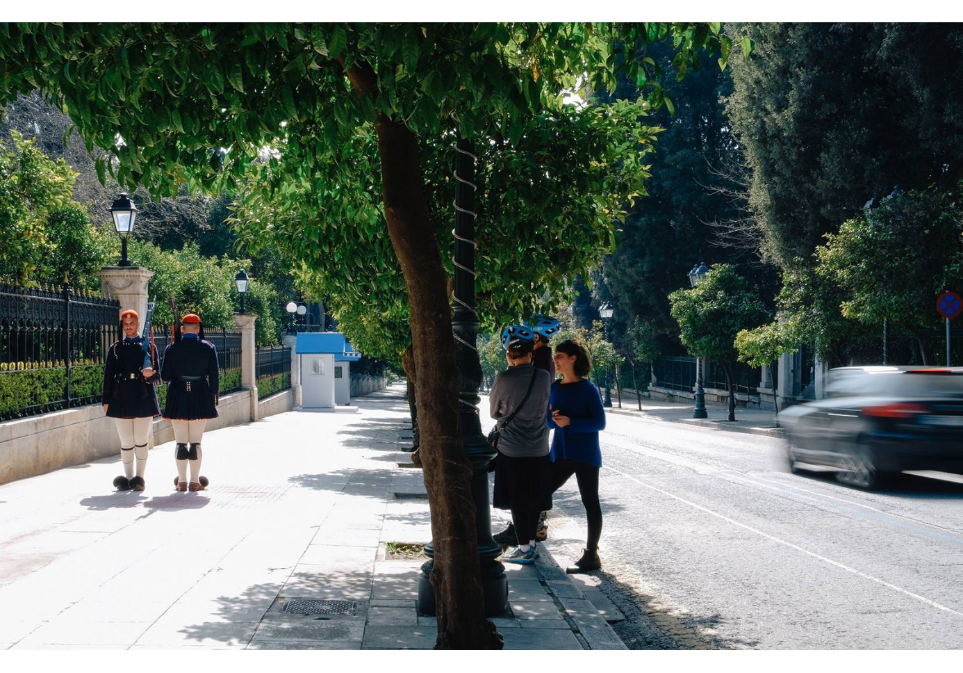 People at Irodou Attikou Street in Athens looking at two Evzones