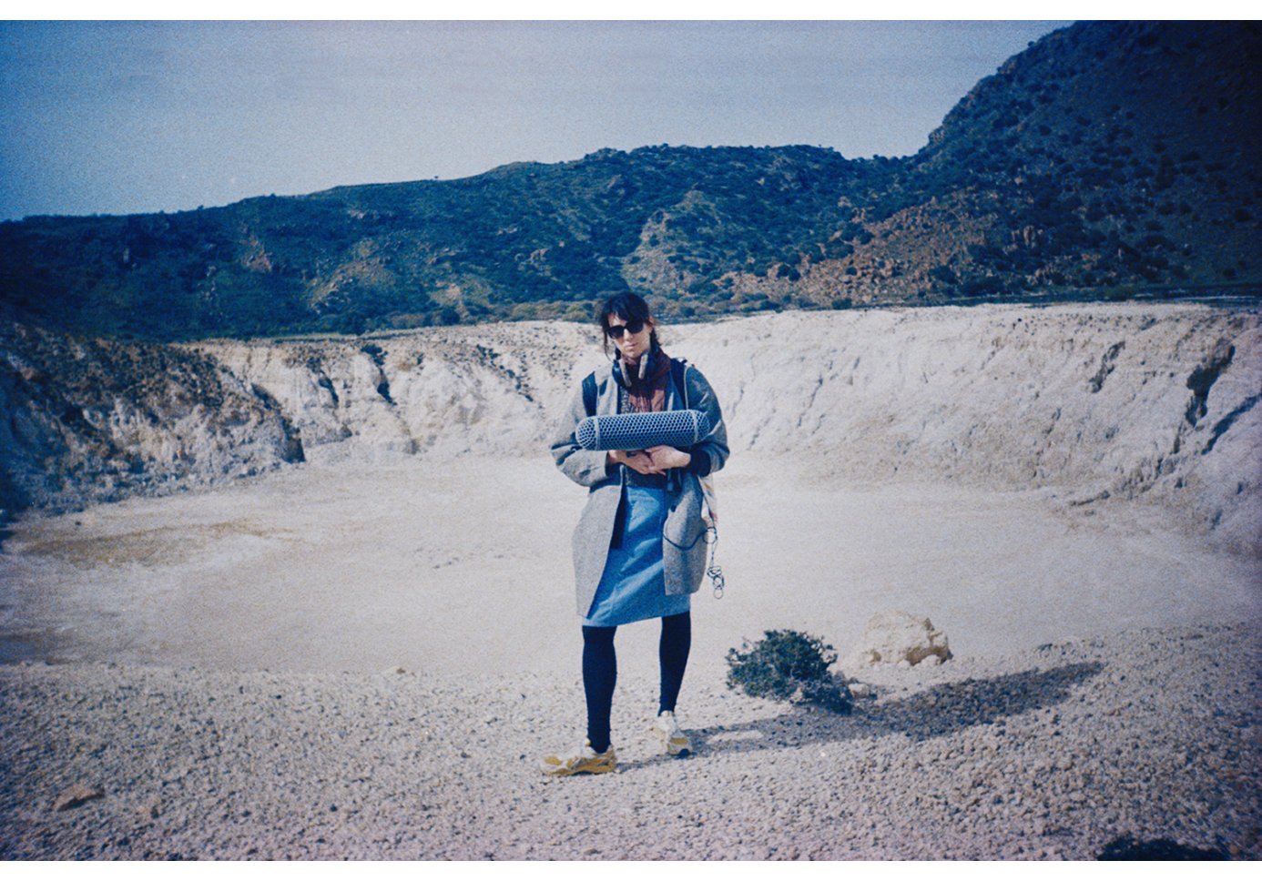 A woman wearing headphones and holding a recording microphone out in the nature