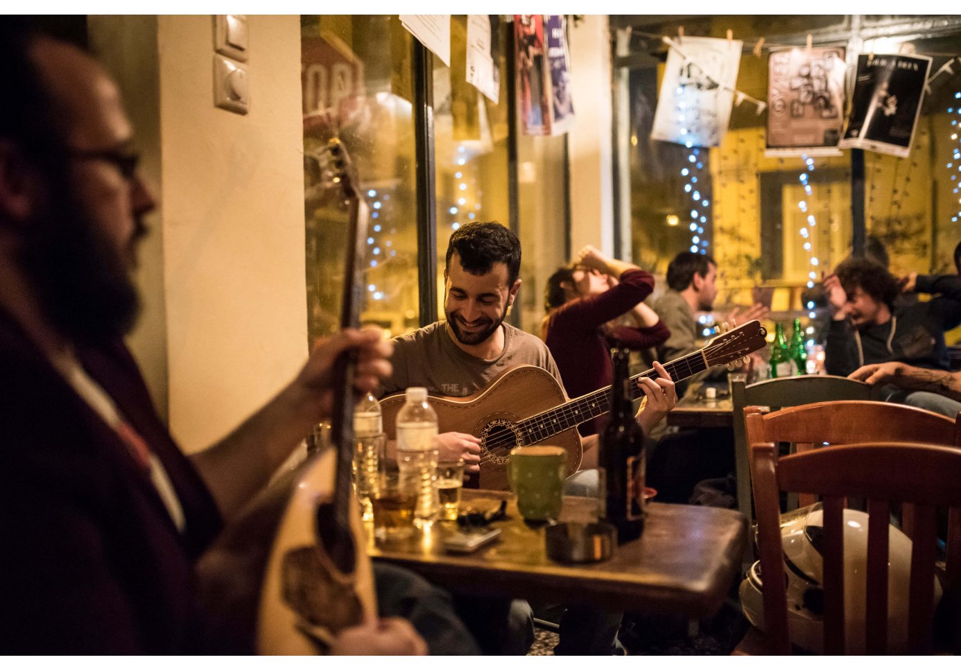 two men playing bouzouki and guitar in front of an ouzeri in Athens