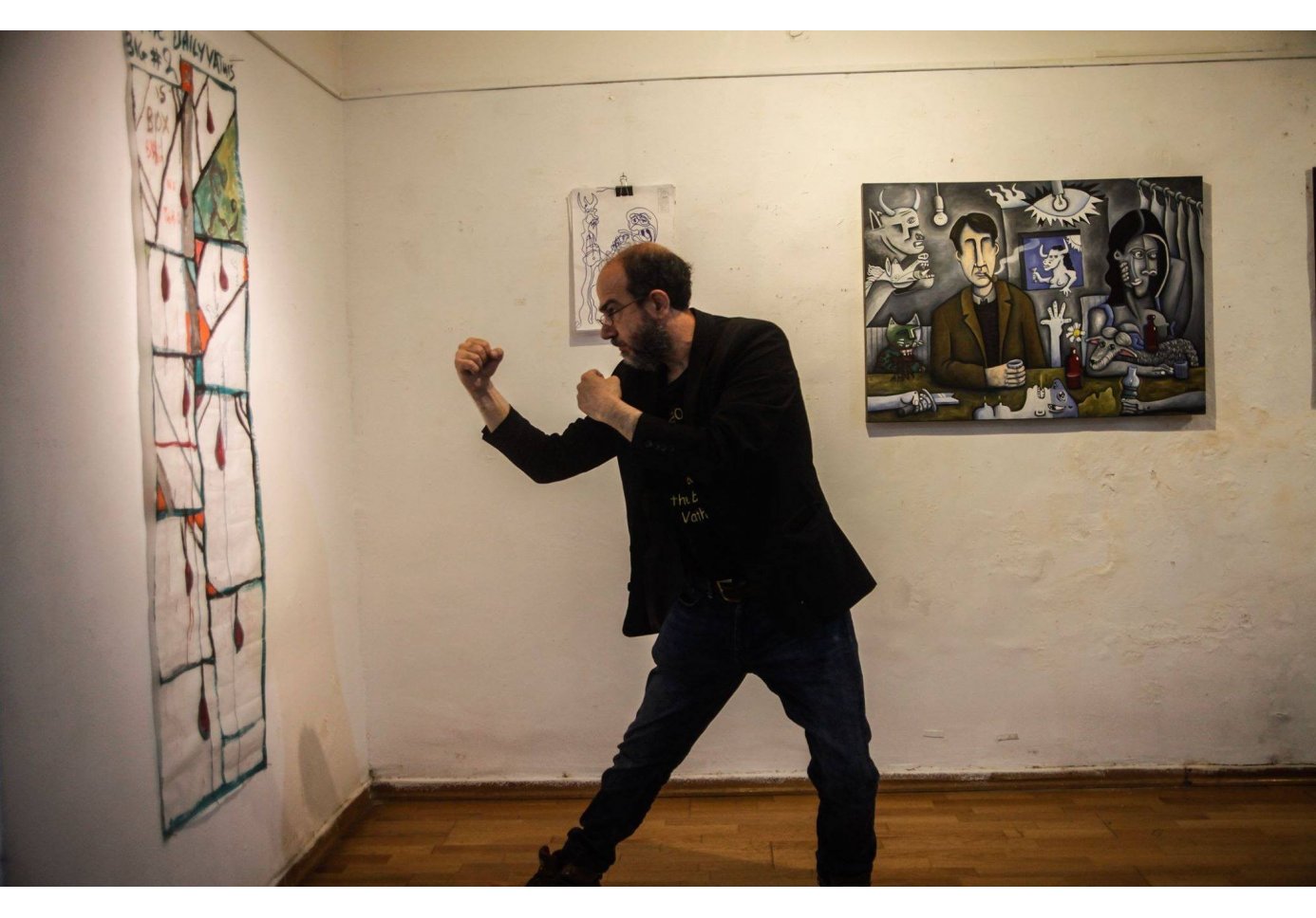 a man posing like boxing with an artwork hanging on the wall in front of him. 