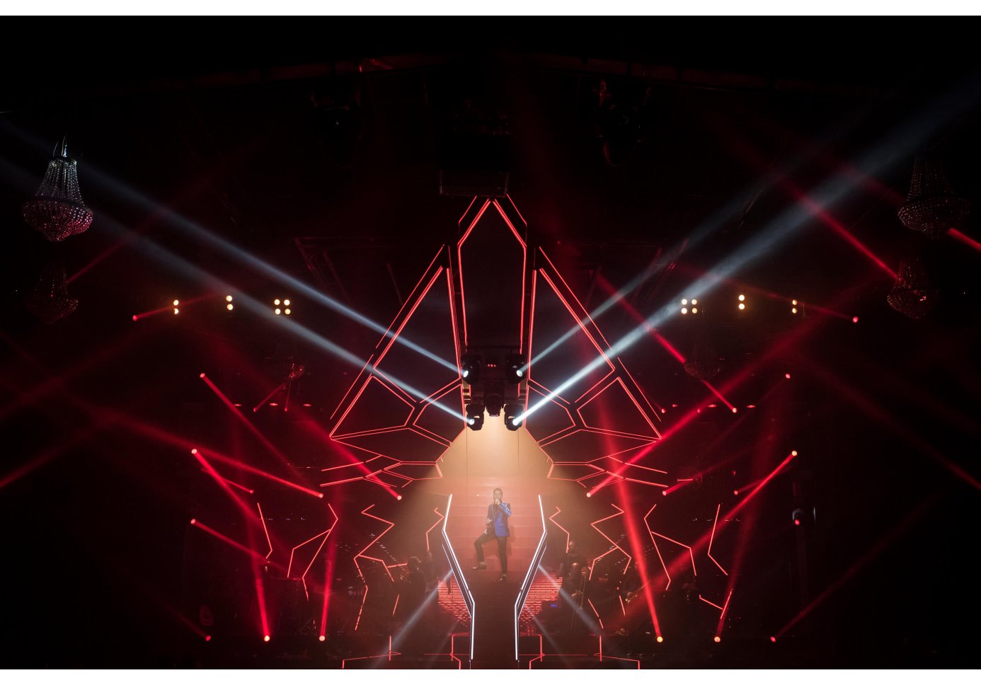 a male singer performing on stage, red and white lighting