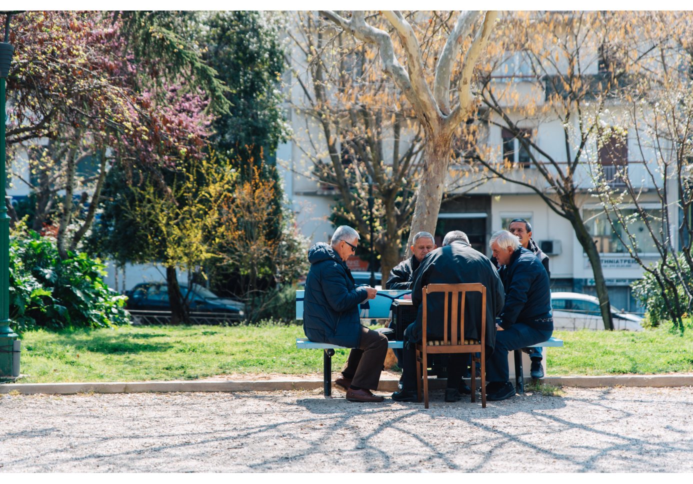 old men sitting around a table at a square.