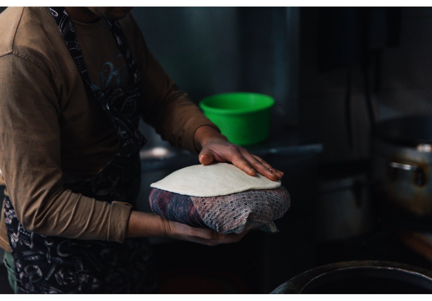 a woman holding dough on a towel in the kitchen.