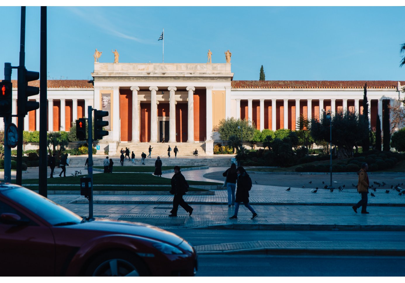 the facade of the National Archaeological Museum, people walking by, cars on the street.