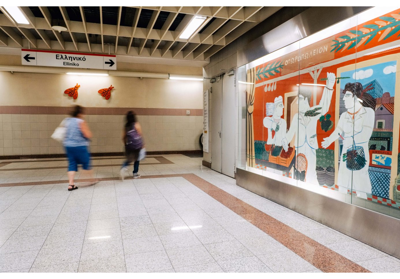 a large-scale artwork in a metro station, people passing by.