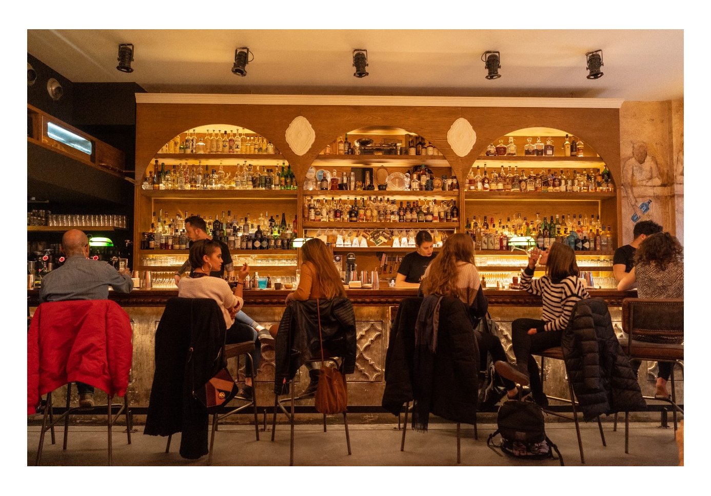 people sitting at a bar, three bartenders