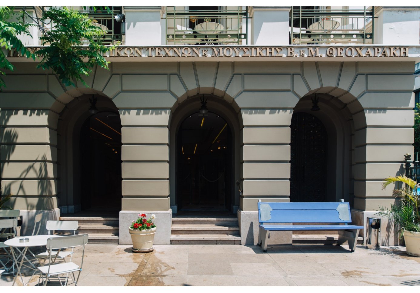 a blue bench next to the entrance of a museum.