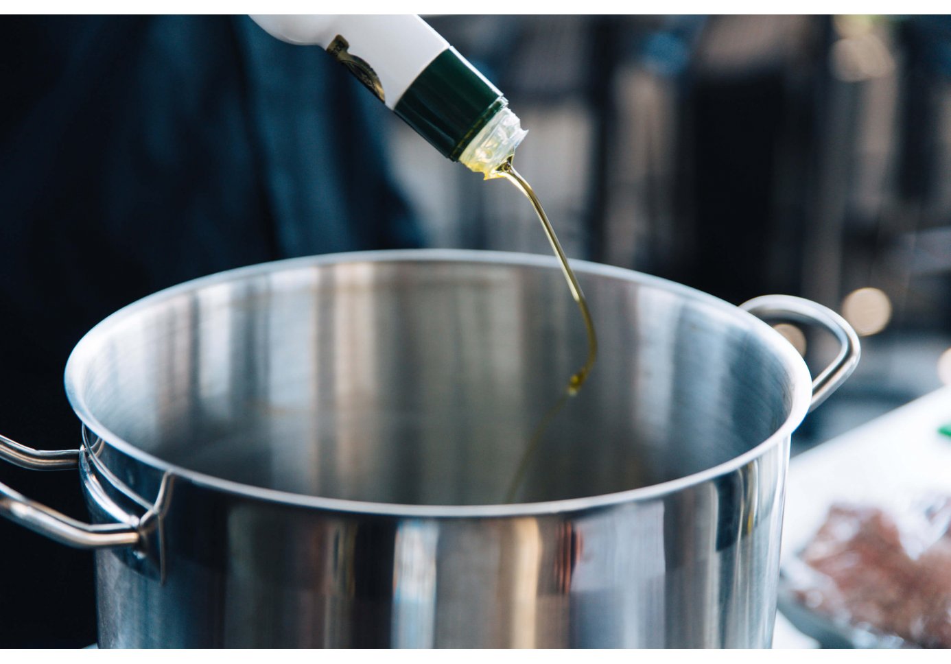 someone pours olive oil into a pot.