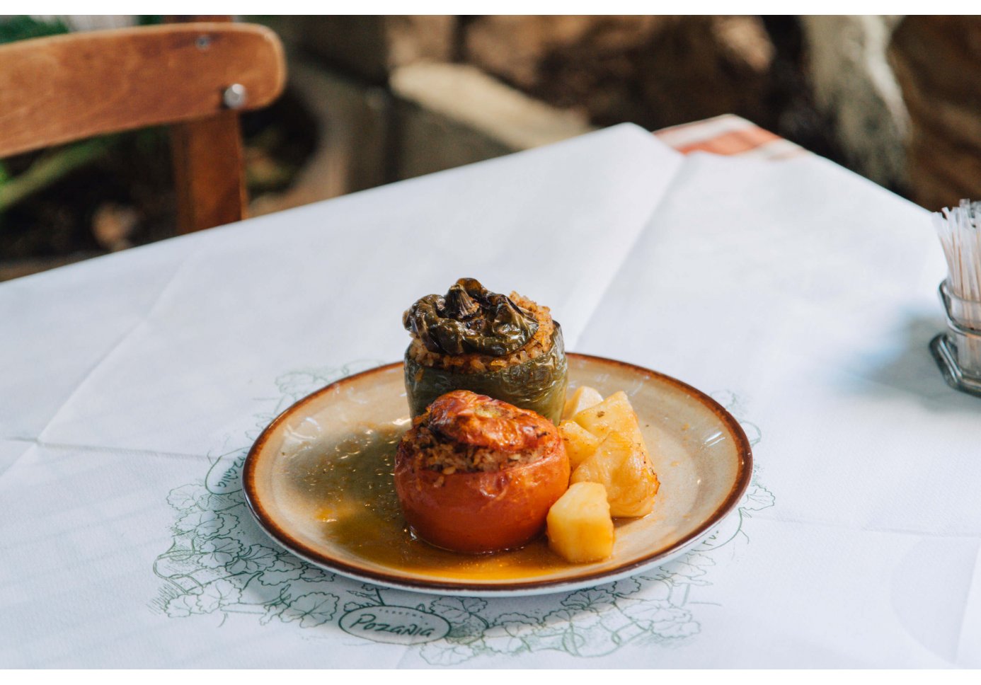 A plate of stuffed peppers and tomatoes, served with roasted potatoes. 