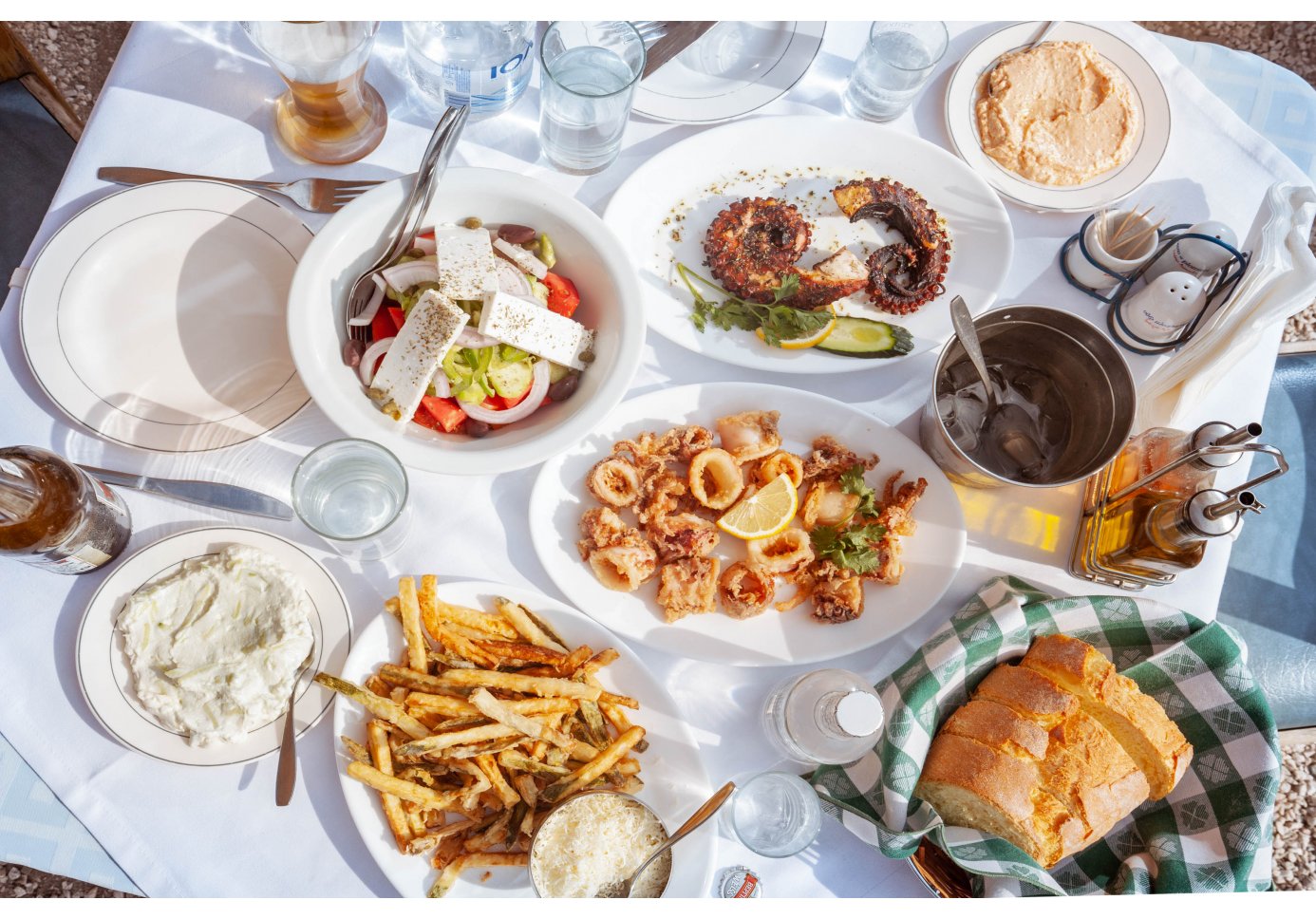 various dishes of seafood and a Greek salad served on a table