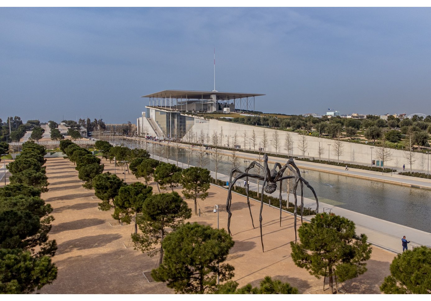 a giant spider installation in an esplanade of a complex, a canal in the picture