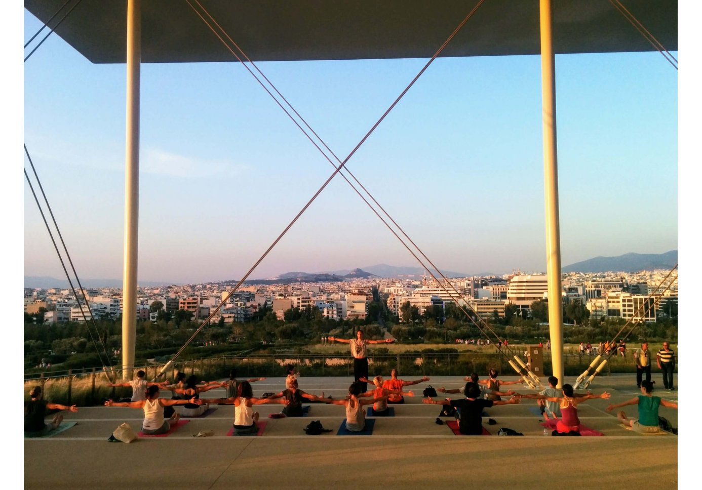 people doing yoga exercises at the steps of a building, a city in the background