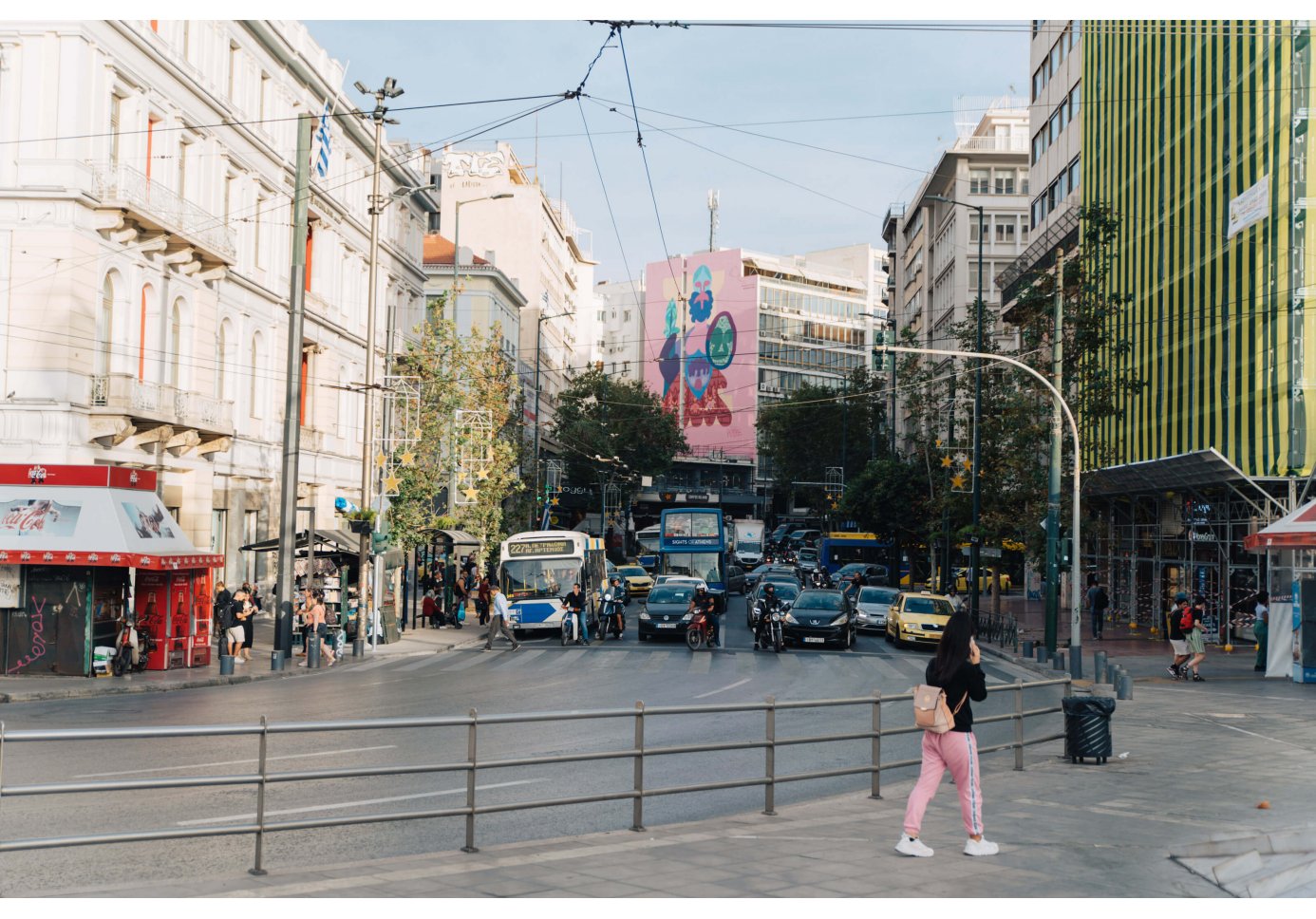 an abstract and colourful mural of godess Athena, traffic jam at a traffic light, passers by, day time.