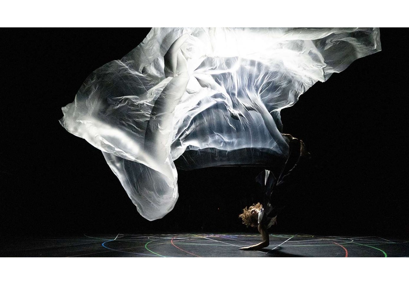 a person performig a dance routine on stage with a huge piece of fabric