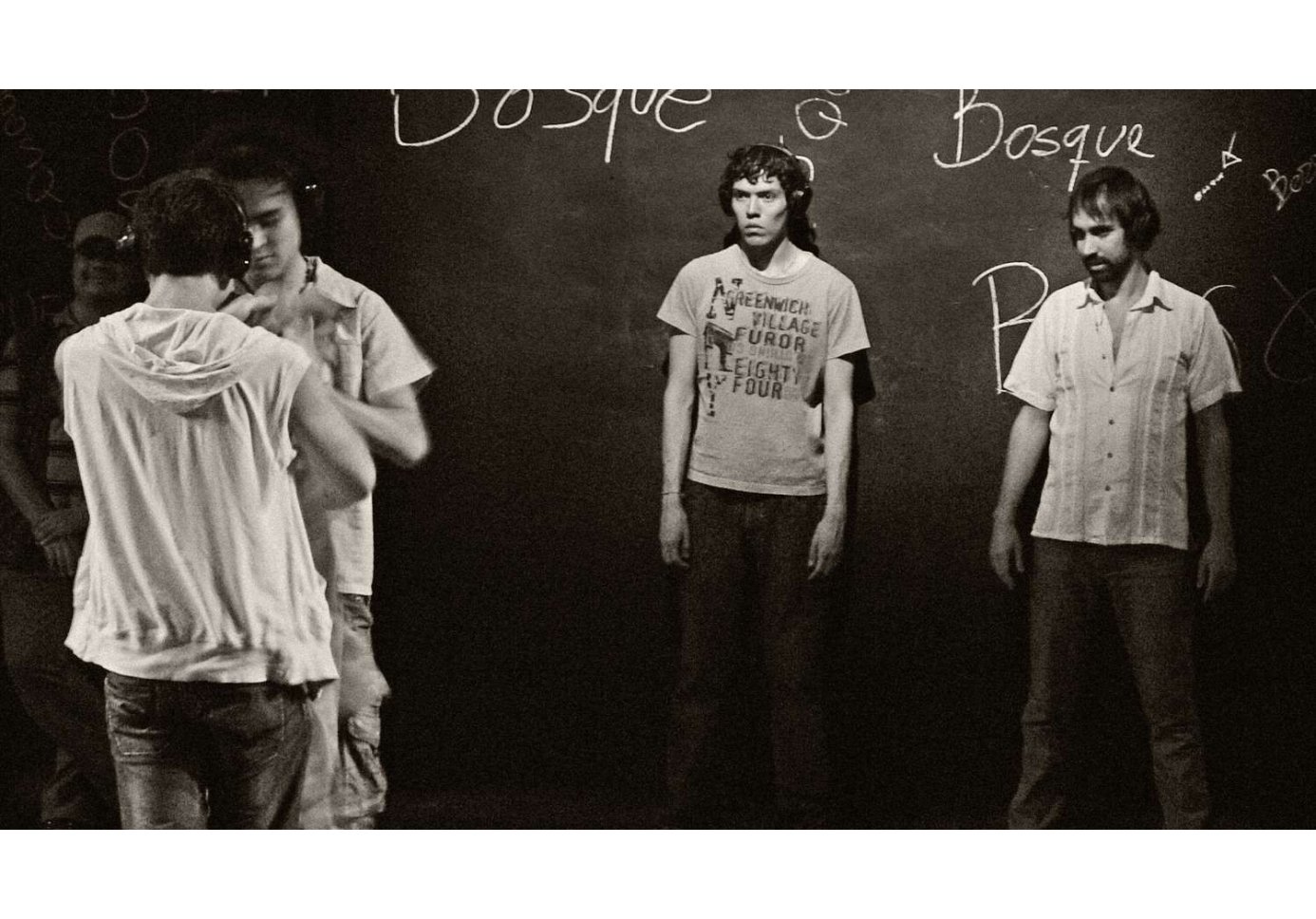 a black and white photo of four people standing on stage