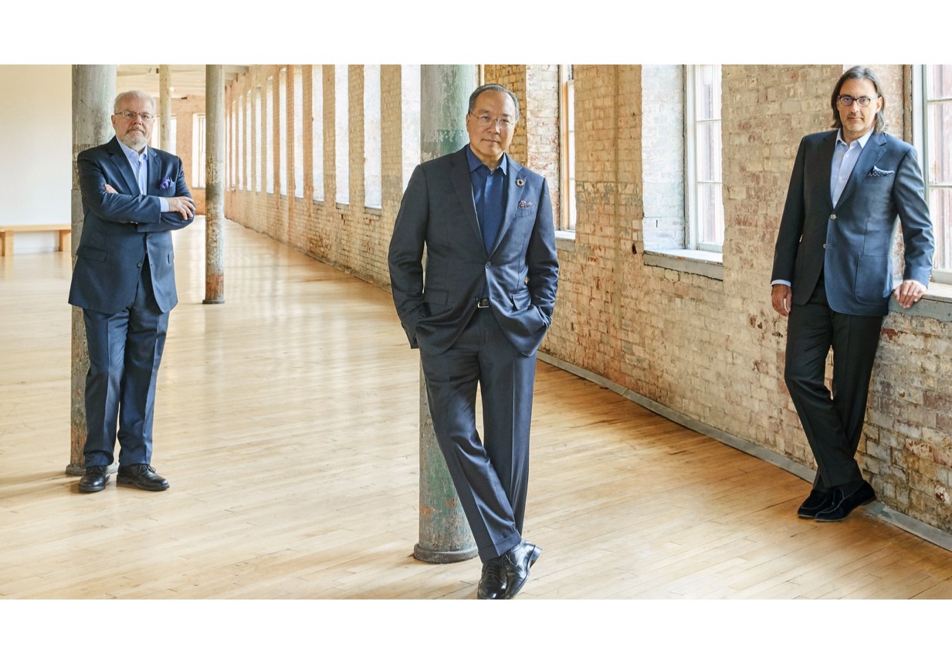 three men in suits looking at the camera in a room